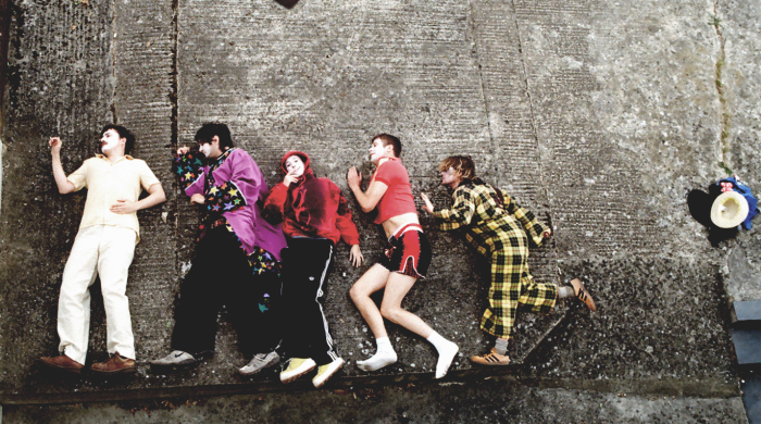 Members of the band 'Sorry' lying down on a concrete floor.